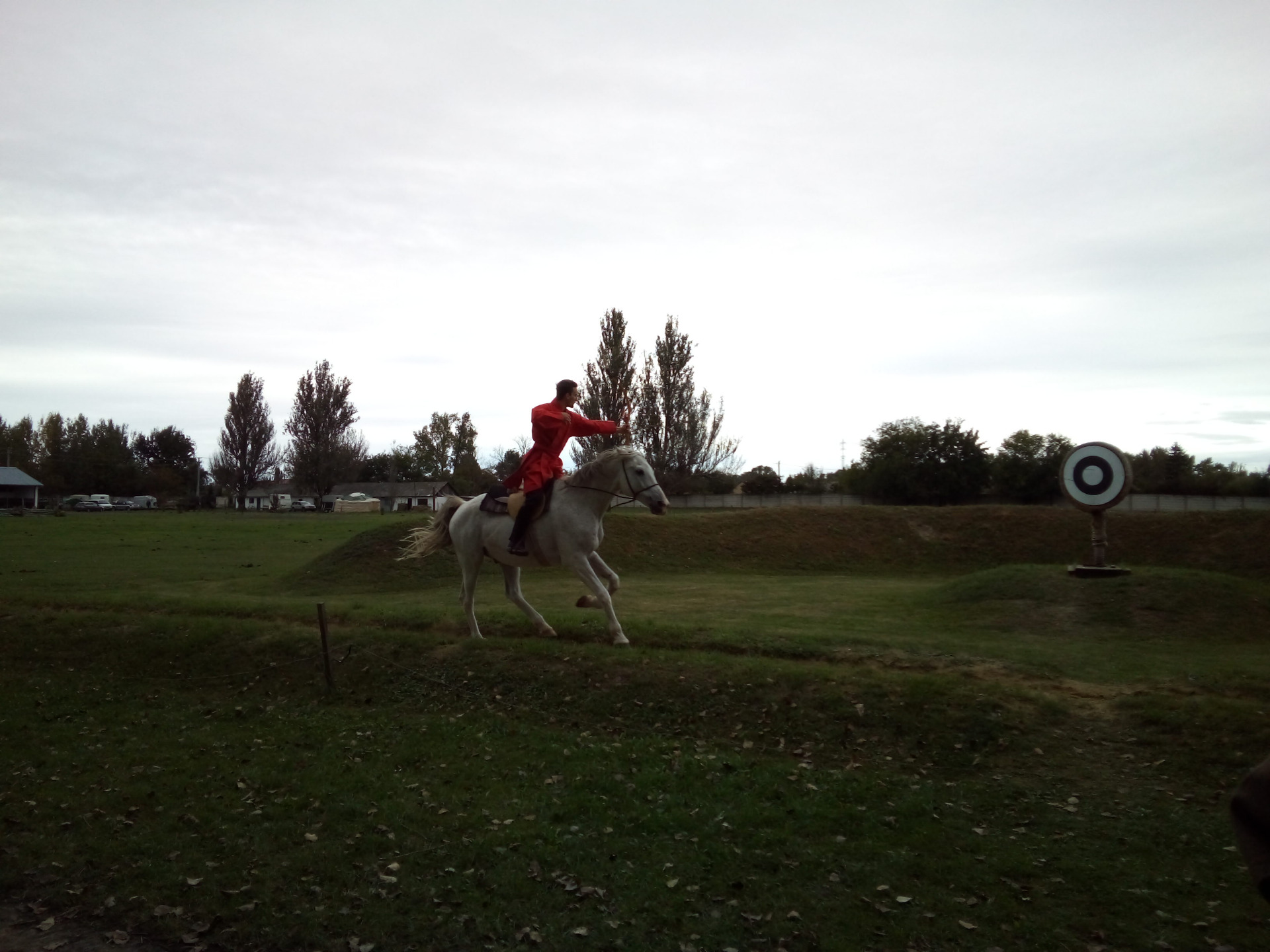 Rider, shooting from the back of a white Shagya Arabian